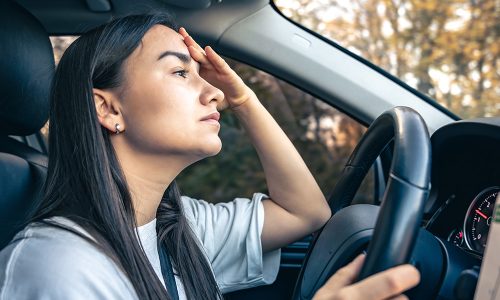 Tired young woman car driver suffering from headache migraine driving vehicle, unwell exhausted girl feeling sick and stressed inside automobile.